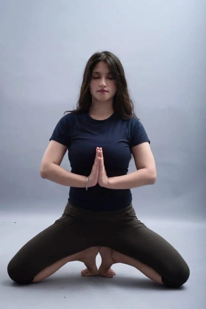 Yogini Pooja holding a seated yoga posture